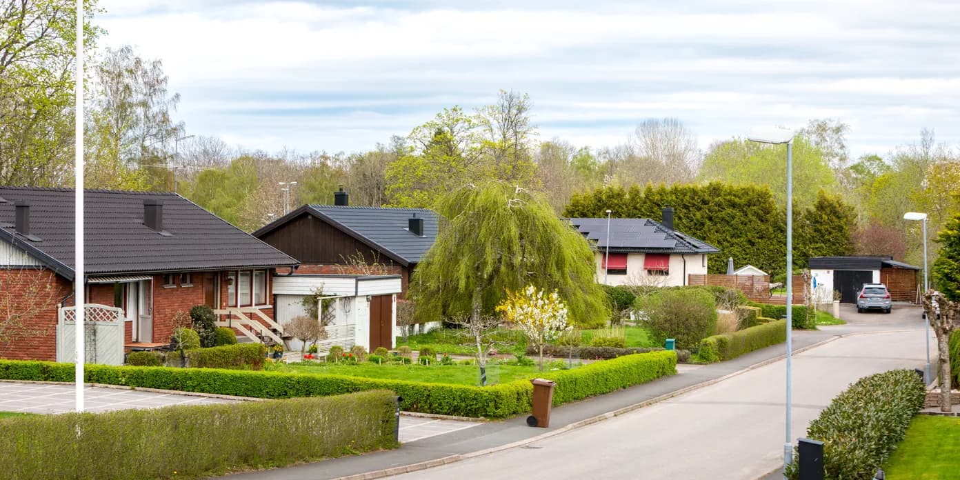 En gata kantad av hus och träd intill en grönskande park