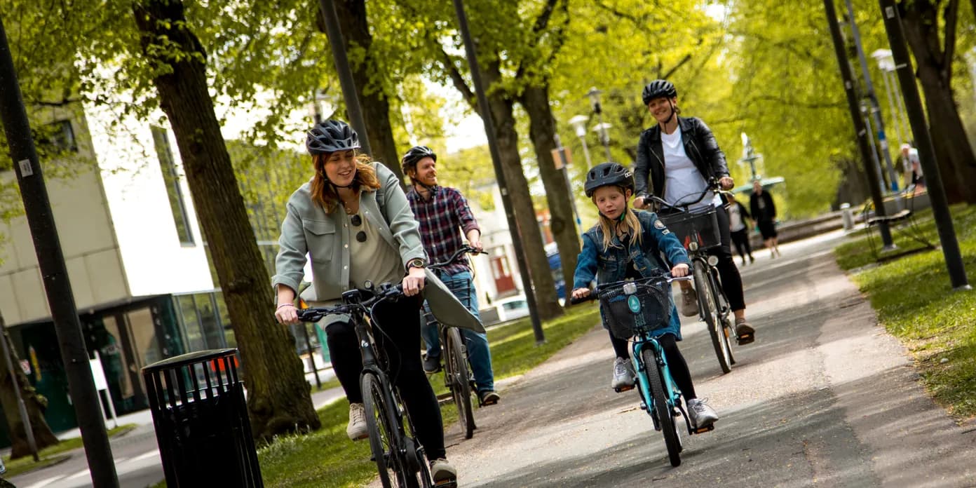 En grupp människor som cyklar på en trottoar