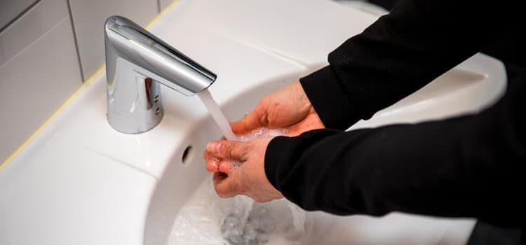 En person som tvättar händerna i ett handfat