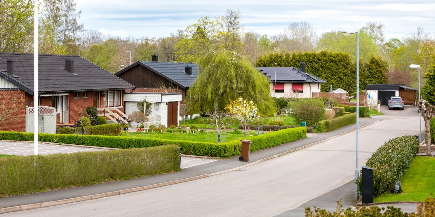 En gata kantad av hus och träd intill en grönskande park