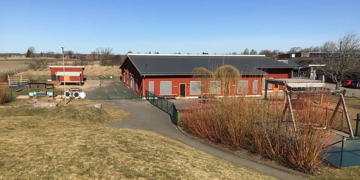 En röd byggnad som ligger på ett grönskande fält
