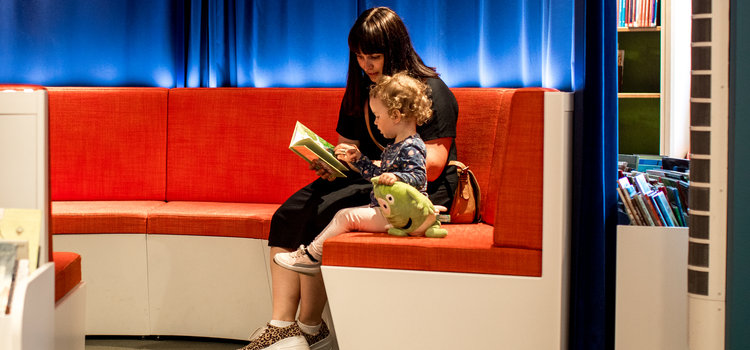 Kvinna som läser högt ur bok tillsammans med barn