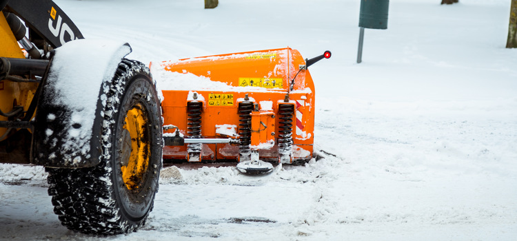En plogbil som röjer snö på en parkering. 