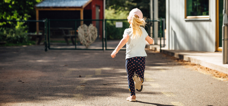 En liten flicka springer på en förskolegård